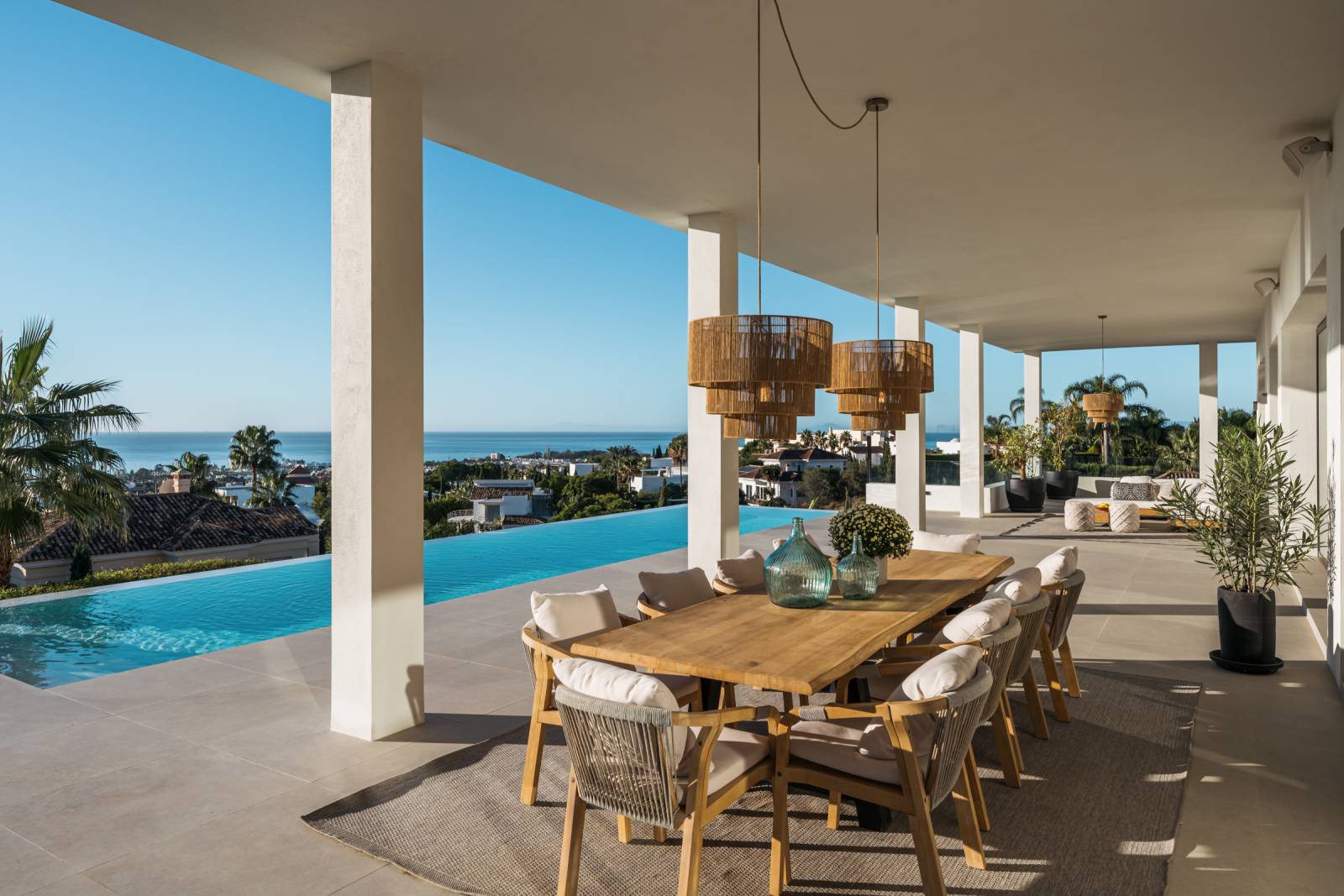 Terrasse extérieure élégante de Villa Olivia avec piscine à débordement, cuisine d’été et espace repas en plein air avec vue sur la mer